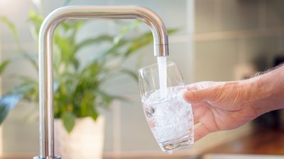 Glas wird mit Trinkwasser aus Wasserhahn gefüllt