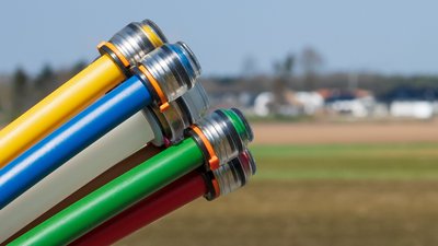 Glasfaserkabel ragen ins Bild hinein, im Hintergrund befindet sich ein Baugebiet